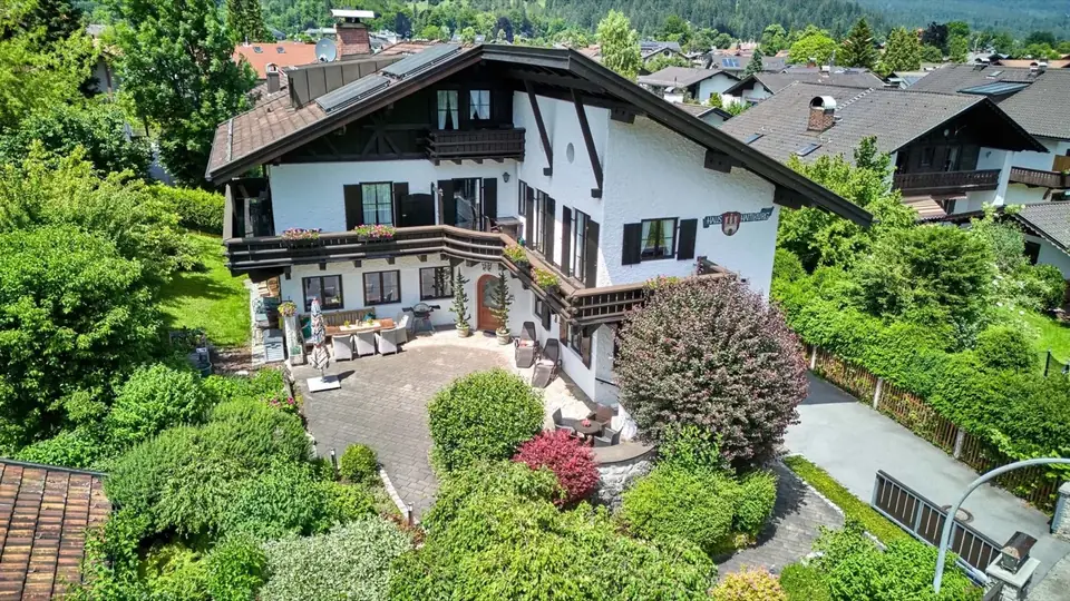 Luftbild des Chalet Haus Hamburg mit dunklem Dach, Garten und Bergen
